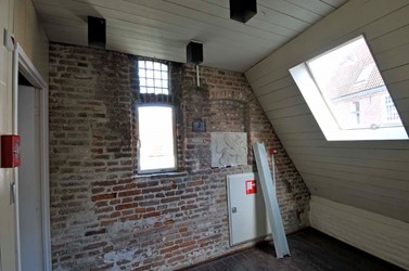 <p>De binnenzijde van de noordgevel van de aanbouw, met centraal een gerestaureerd bakstenen kloostervenster. </p>
